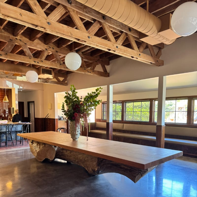 The communal wooden table and exposed rafters inside Bar Auklet.