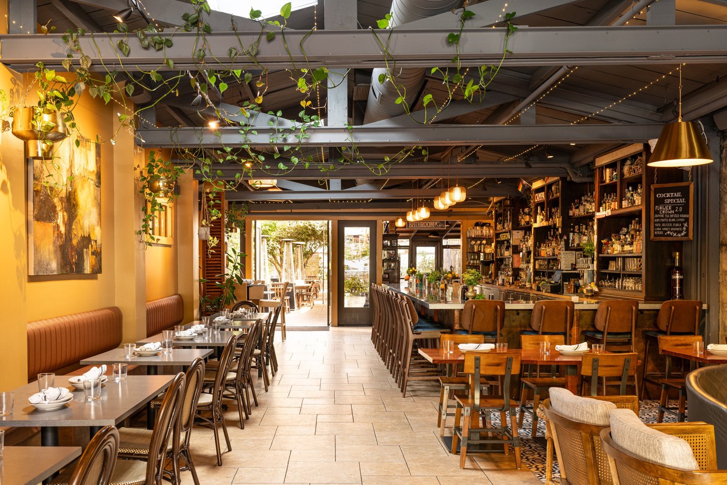The bar and dining room at Lo & Behold, with greenery hanging from the rafters.