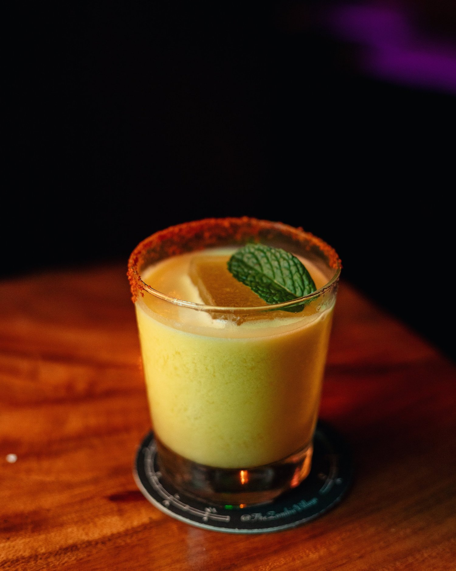 A cocktail with a mint garnish on the bar at Zombie Village.
